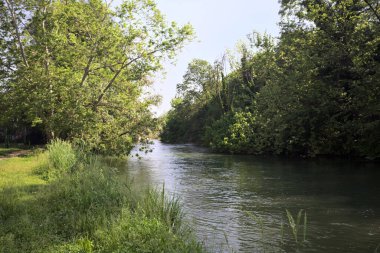 İtalya kırsalındaki bir köyde köprüsü olan bir parktan geçen nehir.