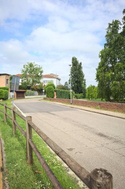 Güneşli bir günde İtalya 'nın kırsal kesimindeki bir köyde parkın kenarından geçen bir sokak.