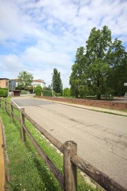 Güneşli bir günde İtalya 'nın kırsal kesimindeki bir köyde parkın kenarından geçen bir sokak.