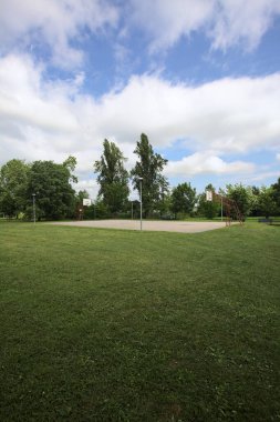Güneşli bir günde, parkın kenarındaki basketbol sahasında bulutlar uzaktan görünüyor.