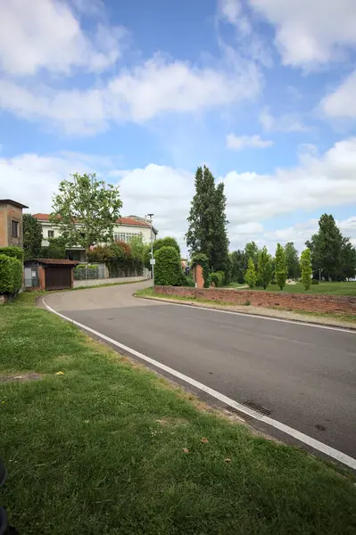 Güneşli bir günde İtalya 'nın kırsal kesimindeki bir köyde parkın kenarından geçen bir sokak.