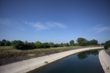 İtalya kırsalında ağaçlarla çevrili bir alanın yanındaki saptırıcı kanal.