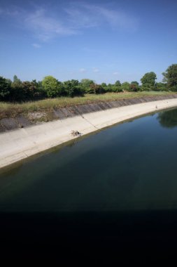İtalya kırsalında ağaçlarla çevrili bir alanın yanındaki saptırıcı kanal.