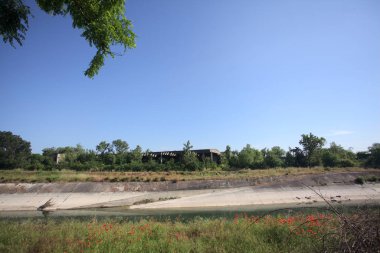 Bir ağaç tarafından çerçevelenmiş güneşli bir günde İtalya kırsalında bir eğlence kanalı.