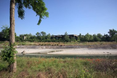 Bir ağaç tarafından çerçevelenmiş güneşli bir günde İtalya kırsalında bir eğlence kanalı.