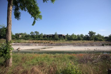 Bir ağaç tarafından çerçevelenmiş güneşli bir günde İtalya kırsalında bir eğlence kanalı.