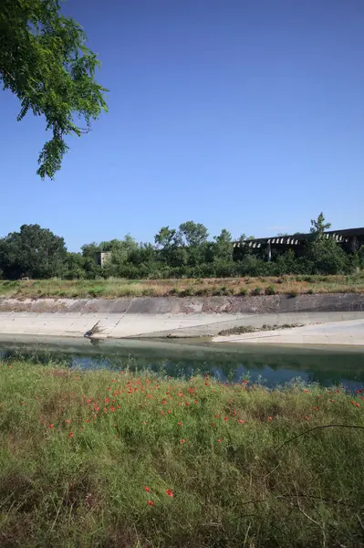 Bir ağaç tarafından çerçevelenmiş güneşli bir günde İtalya kırsalında bir eğlence kanalı.