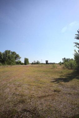 Çamur yolu, güneşli bir günde kuru çimenler ve ağaçlarla kaplı bir bahçenin yanındaki paslı bir bar tarafından kapatıldı.