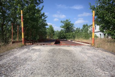 Güneşli bir günde terk edilmiş bir endüstriyel tesiste çalılarla çevrili bir ölçek platformu.