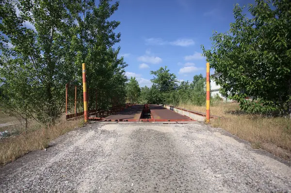 Güneşli bir günde terk edilmiş bir endüstriyel tesiste çalılarla çevrili bir ölçek platformu.