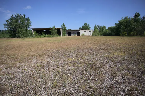 Terk edilmiş bir yerleşkenin depoları güneşli bir günde ağaçlarla çevrili İtalya kırsalında kuru çimenler ve çakıllarla çevrili bir bahçeden görülebiliyor.