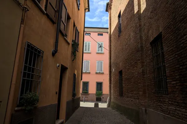 Güneşli bir günde, bir İtalyan kasabasında gölgede, kaldırımlı ve dar bir sokak.