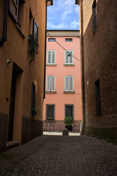 Güneşli bir günde, bir İtalyan kasabasında gölgede, kaldırımlı ve dar bir sokak.
