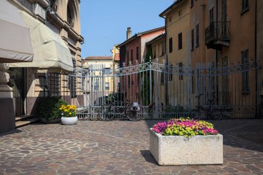 Güneşli bir günde, İtalya 'nın bir şehrinde, tarihi binalar, çiçek saksısı ve demir bir çit arasında.