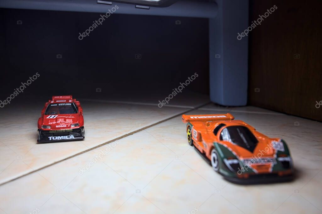 Mantova, Italy - 14TH JUNE 2025 - Hot Wheels and Takara Tomi replicas of a Mazda 787B and a Nissan GTR Skyline Silhouette in the act of racing inside a tunnel