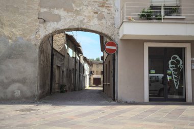 Gölgede, terk edilmiş bir dükkanın sonunda, güneşli bir günde, yolun başındaki bir kemerden görülebilen bir yer.