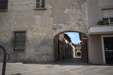 Gölgede, terk edilmiş bir dükkanın sonunda, güneşli bir günde, yolun başındaki bir kemerden görülebilen bir yer.