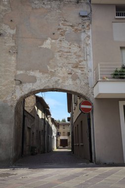 Gölgede, terk edilmiş bir dükkanın sonunda, güneşli bir günde, yolun başındaki bir kemerden görülebilen bir yer.