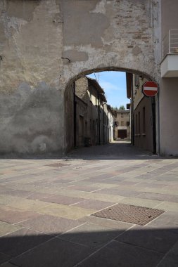 Gölgede, terk edilmiş bir dükkanın sonunda, güneşli bir günde, yolun başındaki bir kemerden görülebilen bir yer.