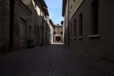 Gölgede, terk edilmiş bir dükkanın sonunda, güneşli bir günde, yolun başındaki bir kemerden görülebilen bir yer.