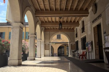 Güneşli bir günde bir İtalyan kasabasının meydanında tarihi bir binanın verandası.