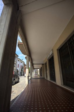 Güneşli bir günde sokağın kenarındaki metal kepenklerle kapatılmış bir binanın altındaki modern veranda.