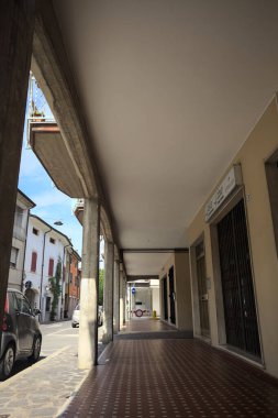 Güneşli bir günde sokağın kenarındaki metal kepenklerle kapatılmış bir binanın altındaki modern veranda.