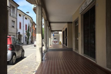 Güneşli bir günde sokağın kenarındaki metal kepenklerle kapatılmış bir binanın altındaki modern veranda.