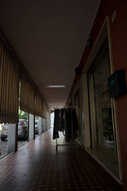 Gölgede veranda, sütunlar ve sandalyeler arasındaki boşluklarda perdeler ve ortasında bir İtalyan kasabasında elbise askısı.