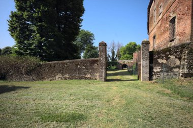 Bir şatonun kenarındaki patika, uzaktaki bir köprünün kemerlerinin altından geçiyor, yere düşen ağaçların gölgeleriyle.