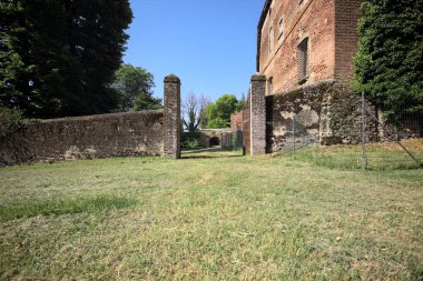 Bir şatonun kenarındaki patika, uzaktaki bir köprünün kemerlerinin altından geçiyor, yere düşen ağaçların gölgeleriyle.