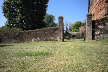 Bir şatonun kenarındaki patika, uzaktaki bir köprünün kemerlerinin altından geçiyor, yere düşen ağaçların gölgeleriyle.