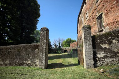 Bir şatonun kenarındaki patika, uzaktaki bir köprünün kemerlerinin altından geçiyor, yere düşen ağaçların gölgeleriyle.