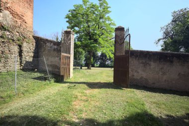 İtalya kırsalında güneşli bir günde, üzerinde ağaçlar olan bir çimenliğe açılan bir duvarın kapısını aç.