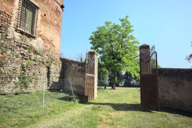 İtalya kırsalında güneşli bir günde, üzerinde ağaçlar olan bir çimenliğe açılan bir duvarın kapısını aç.