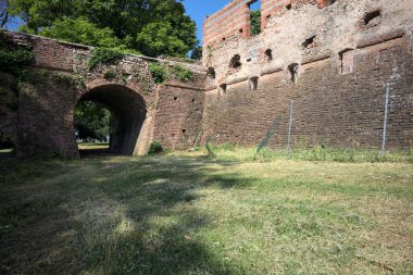 İtalya kırsalında güneşli bir günde terk edilmiş bir kalenin yanındaki tuğla köprünün altından geçen patika.