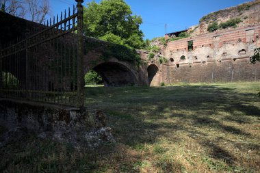 Terk edilmiş bir kalenin dış cephesi ve köprüsü güneşli bir günde İtalya kırsalında bir çitin arkasında görüldü.