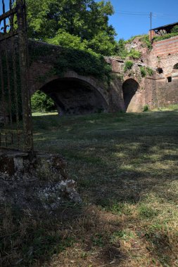 Terk edilmiş bir kalenin dış cephesi ve köprüsü güneşli bir günde İtalya kırsalında bir çitin arkasında görüldü.
