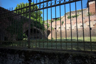 Terk edilmiş bir kalenin dış cephesi ve köprüsü güneşli bir günde İtalya kırsalında bir çitin arkasında görüldü.