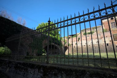 Terk edilmiş bir kalenin dış cephesi ve köprüsü güneşli bir günde İtalya kırsalında bir çitin arkasında görüldü.