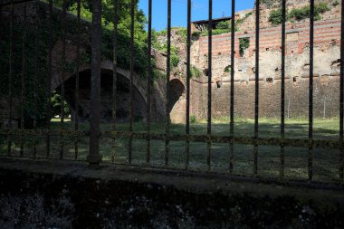 Terk edilmiş bir kalenin dış cephesi ve köprüsü güneşli bir günde İtalya kırsalında bir çitin arkasında görüldü.