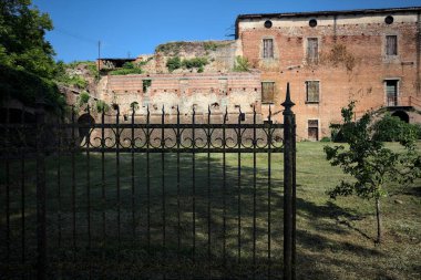 Terk edilmiş bir kalenin dış cephesi ve köprüsü güneşli bir günde İtalya kırsalında bir çitin arkasında görüldü.