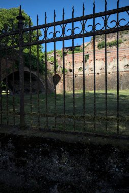 Terk edilmiş bir kalenin dış cephesi ve köprüsü güneşli bir günde İtalya kırsalında bir çitin arkasında görüldü.