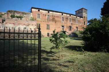 Terk edilmiş bir kalenin dış cephesi ve köprüsü güneşli bir günde İtalya kırsalında bir çitin arkasında görüldü.