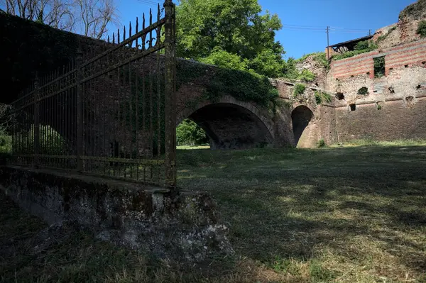 Terk edilmiş bir kalenin dış cephesi ve köprüsü güneşli bir günde İtalya kırsalında bir çitin arkasında görüldü.