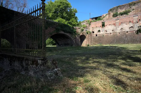 Terk edilmiş bir kalenin dış cephesi ve köprüsü güneşli bir günde İtalya kırsalında bir çitin arkasında görüldü.