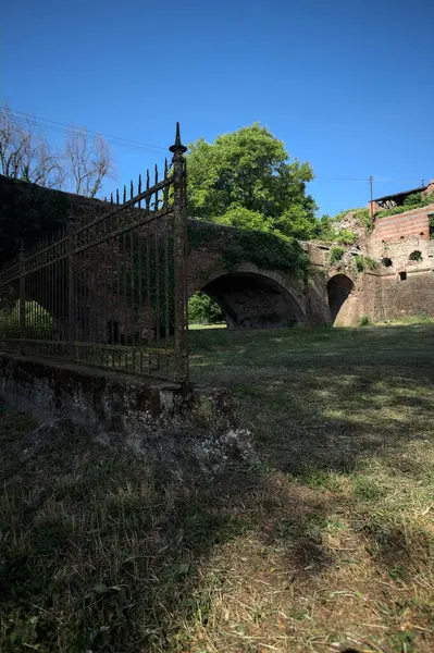 Terk edilmiş bir kalenin dış cephesi ve köprüsü güneşli bir günde İtalya kırsalında bir çitin arkasında görüldü.