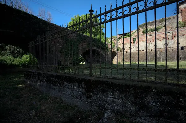 Terk edilmiş bir kalenin dış cephesi ve köprüsü güneşli bir günde İtalya kırsalında bir çitin arkasında görüldü.