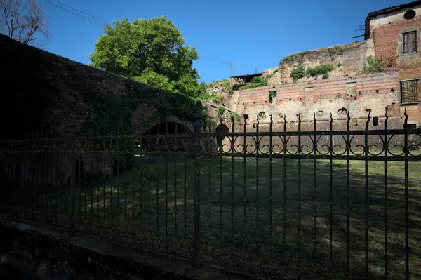 Terk edilmiş bir kalenin dış cephesi ve köprüsü güneşli bir günde İtalya kırsalında bir çitin arkasında görüldü.