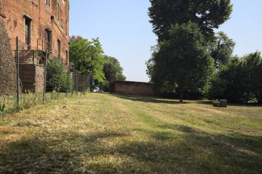 Terk edilmiş bir şatonun cephesi ve önünde de güneşli bir günde İtalya kırsalında bir çimen.